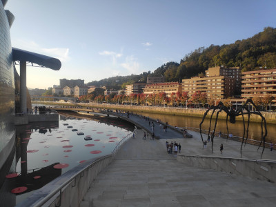 Spindly spider statue outside the Guggenheim, near sunset, lots of people hanging around.
