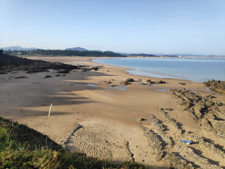 A very very long beach, partially covered in shadow.