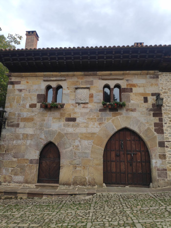 The front of a building. Two ornate wooden doors with pointy archways. Lots of stone.