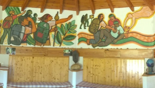 Wall paintings depicting the philosophy of the albergue. Some pilgrims walking the Camino, then some pilgrims helping someone who appears to have fallen over.